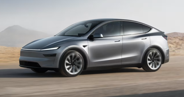 Tesla Model Y crossover EV in silver on open road—mid-size electric SUV.